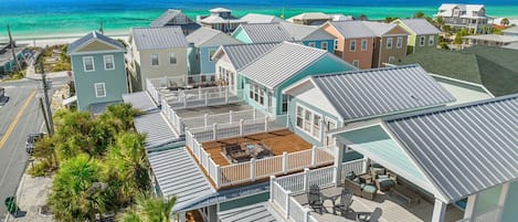 Un área residencial costera con varias casas, algunas con terrazas y barandillas, y una vista despejada del océano.