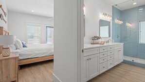 A modern bathroom with a large mirror, a sink, and a shower area. - Spectacular 3br 4ba w/ Private Pool, 2 Min Walk to Beach - Sleeps 15! (Panama City Beach)