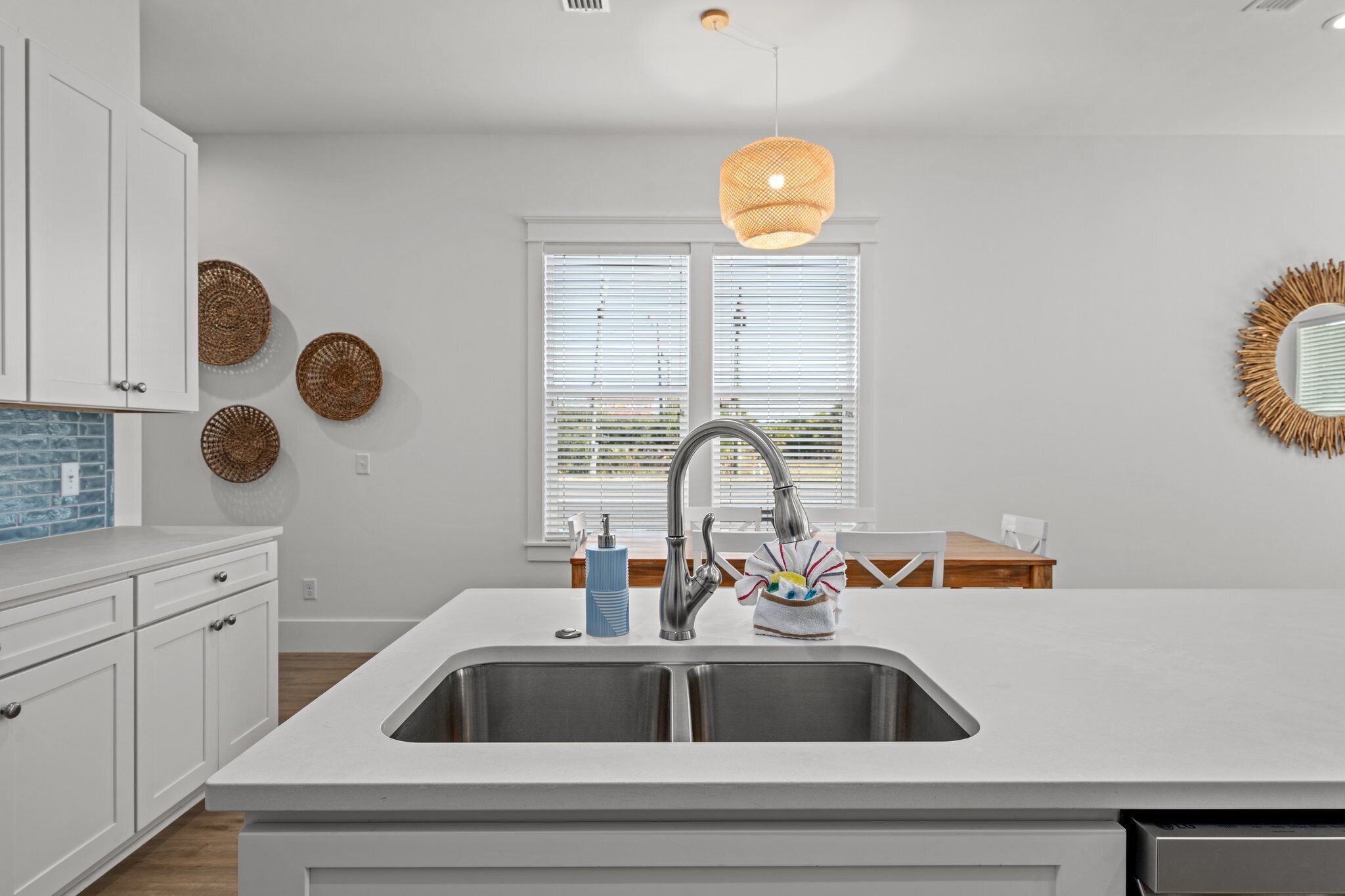 A modern kitchen with white cabinetry, a stainless steel sink, and a hanging pendant light.