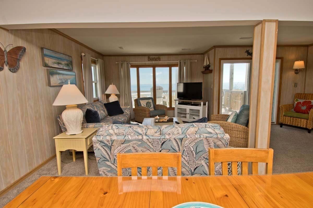 Une chambre d’hôtel avec un balcon, une télévision, un canapé et une table à manger.