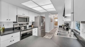 A modern kitchen with white cabinets, stainless steel appliances, a large island, and a walk-in pantry.