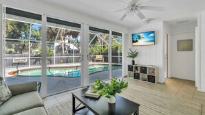A spacious living room with a large sliding glass door leading to a pool area.