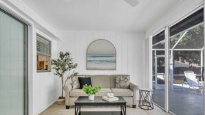 A modern living room with a sofa, coffee table, and a large window overlooking a balcony.
