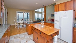 A modern kitchen with wooden cabinets, a granite countertop, and a built-in refrigerator. - Witt's Inn, Soundfront House in Emerald Isle, NC! (Emerald Isle)