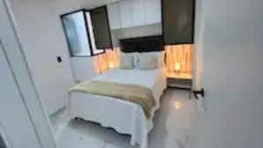 Un dormitorio moderno con una cama, mesitas de noche y un ventanal.