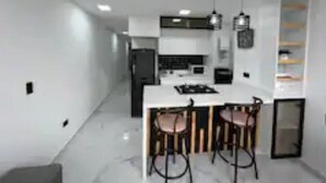 Una cocina moderna con una isla central, taburetes de bar, iluminación colgante y armarios empotrados.
