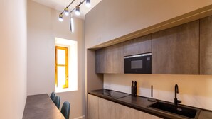 A modern kitchen with a built-in microwave, a black sink, and a window providing natural light.