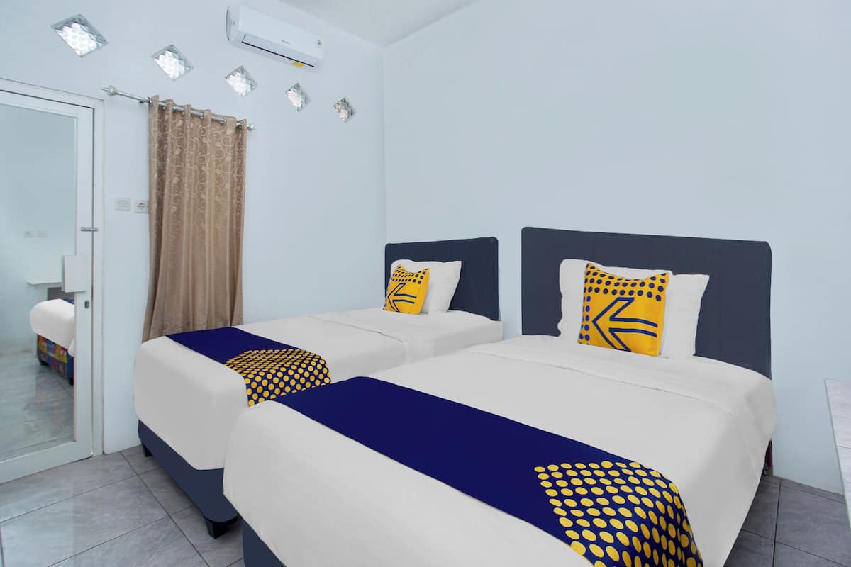 A hotel room with two beds, a bathroom, and a view of the city.