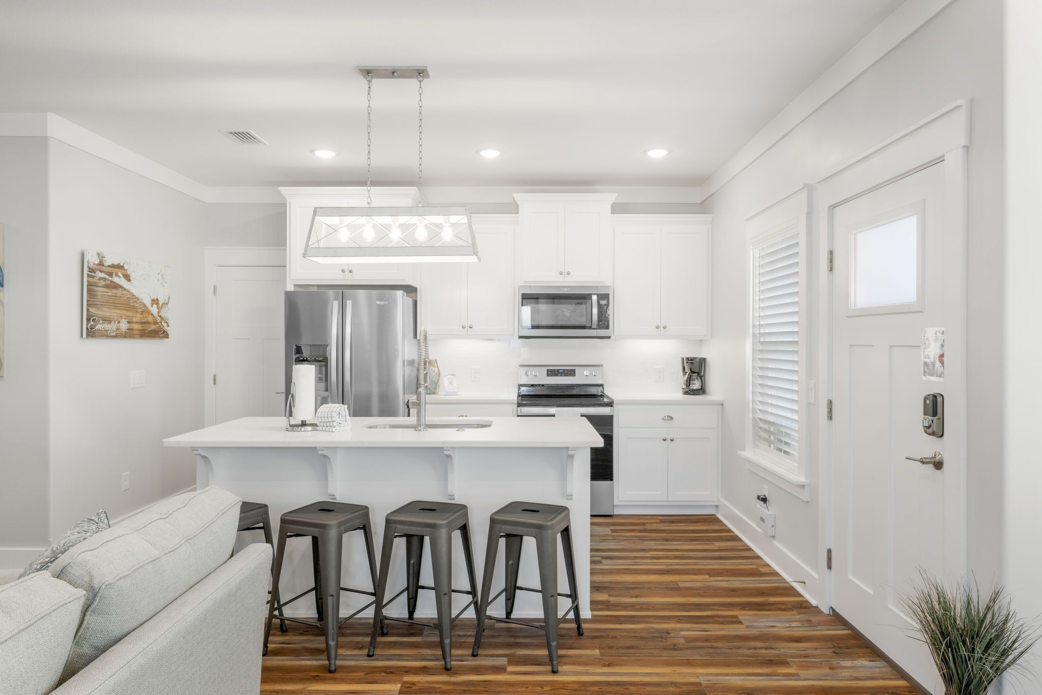 Una cocina moderna con armarios blancos, electrodomésticos de acero inoxidable y una isla central con taburetes.