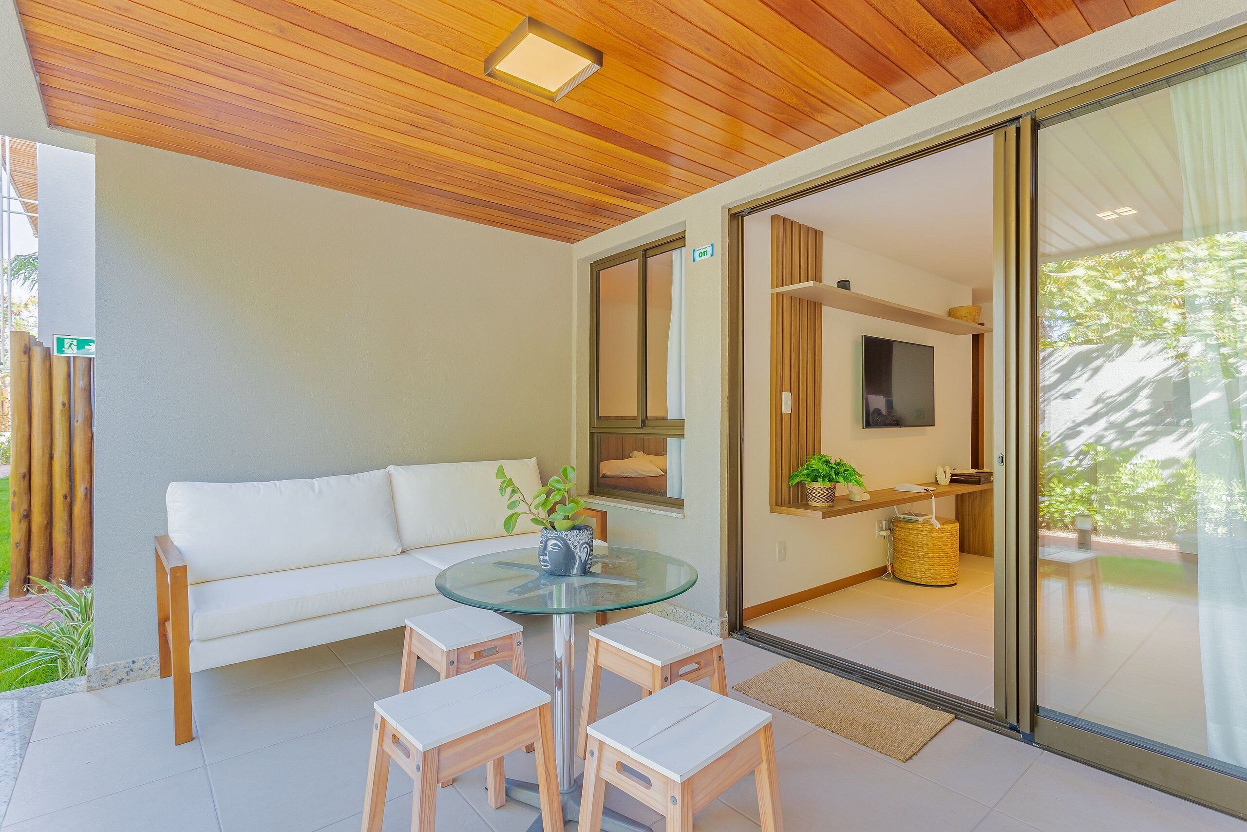 Un salon moderne avec une table en verre, un canapé blanc et des tabourets en bois.
