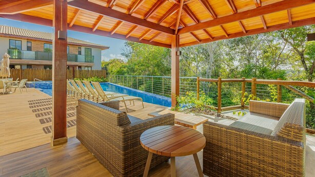 Un espacio al aire libre cubierto con muebles de mimbre, una piscina y vista a una casa.