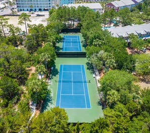 An aerial view of a tennis court complex surrounded by trees and buildings.