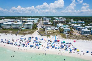 A coastal resort with multiple buildings, a sandy beach, and numerous umbrellas.