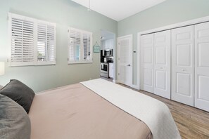 A bedroom with a bed, a nightstand, a dresser, and a closet.
