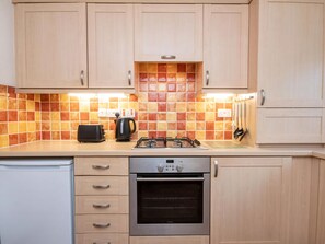 A kitchen with wooden cabinets, a gas stove, an oven, a toaster, and a kettle. - 2 bedroom accommodation in Inverness (Inverness)