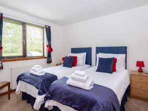 A hotel room with two beds, each with blue and white bedding, red pillows, and a red lamp on a wooden nightstand. - 2 bedroom accommodation in Inverness (Inverness)