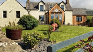 A two-story house with a stone facade, a wooden extension, and a well-maintained lawn. - White House - UKC6895 (Golspie)