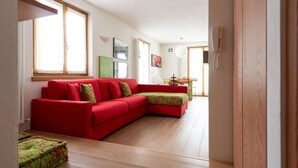 Uma sala de estar moderna com um sofá seccional vermelho, piso de madeira e uma área de jantar com mesa e cadeiras.