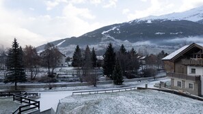 Een besneeuwd landschap met een berg op de achtergrond, een weg en gebouwen met uitzicht op het panorama.