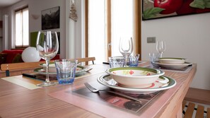 Een eettafel gedekt met borden, kommen, glazen en bestek.