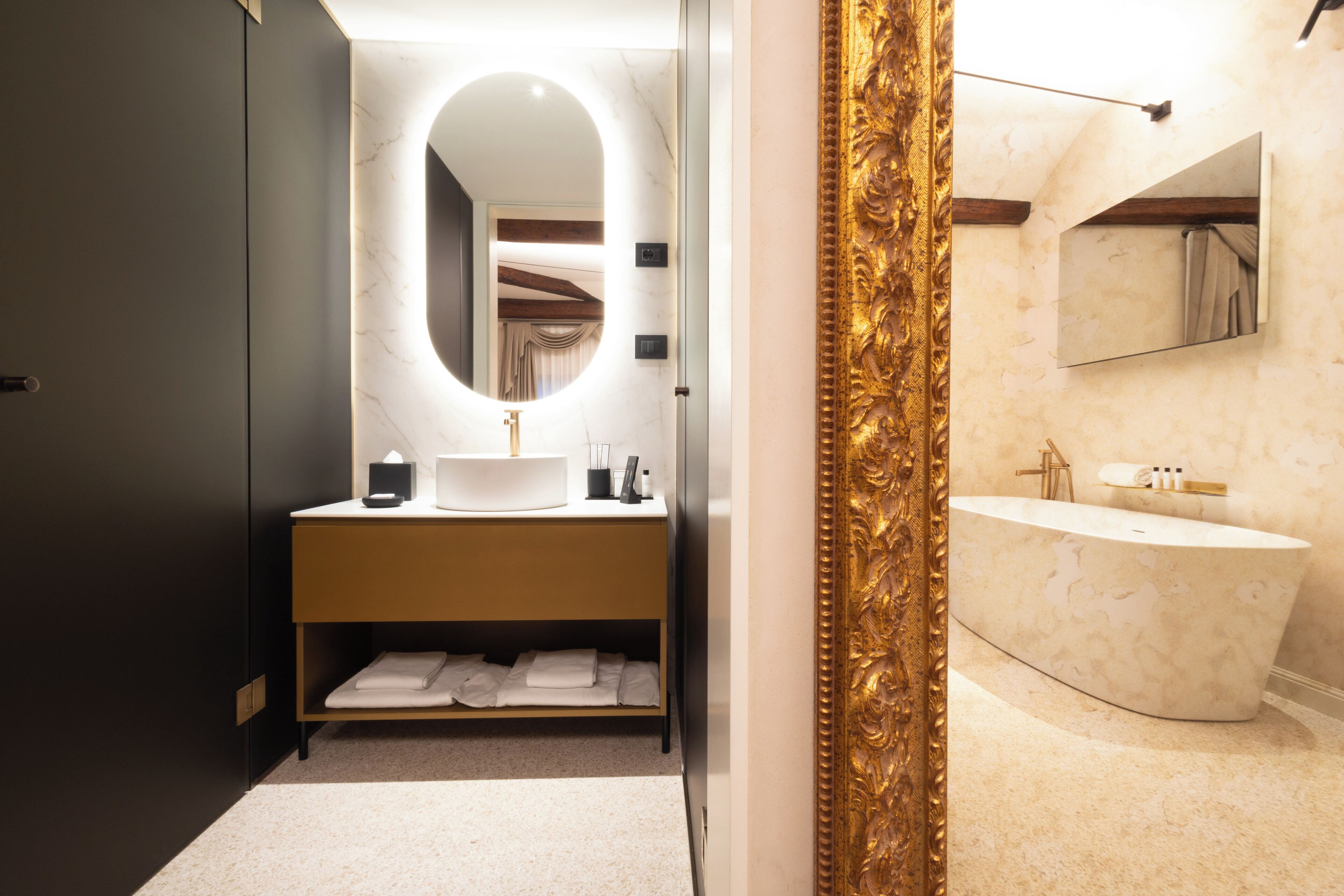A modern bathroom with a vanity, a freestanding bathtub, a large mirror, and a gold-framed mirror.