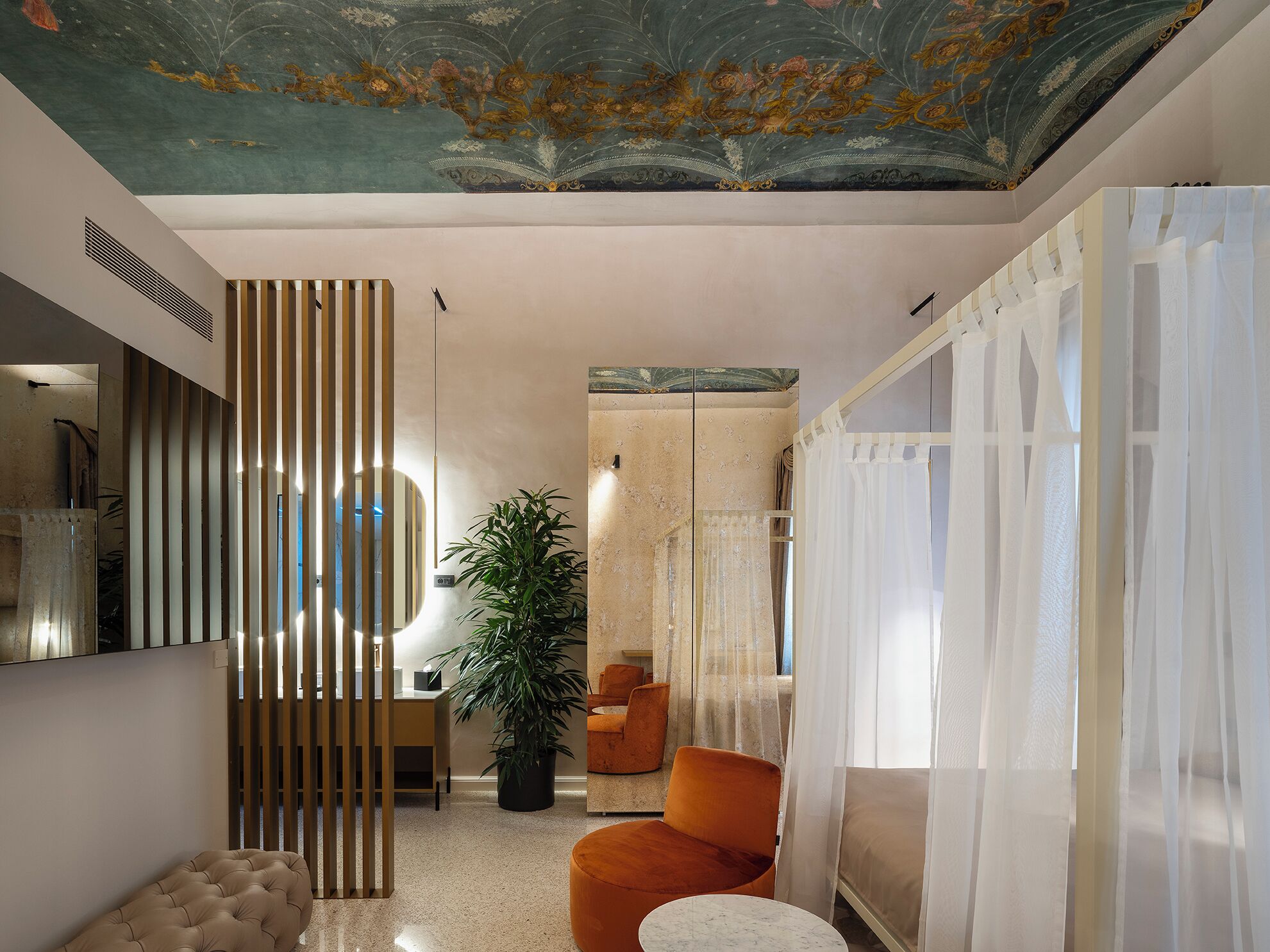 A modern interior with a decorative ceiling, a seating area with a sofa and armchair, a potted plant, and a wall-mounted mirror.