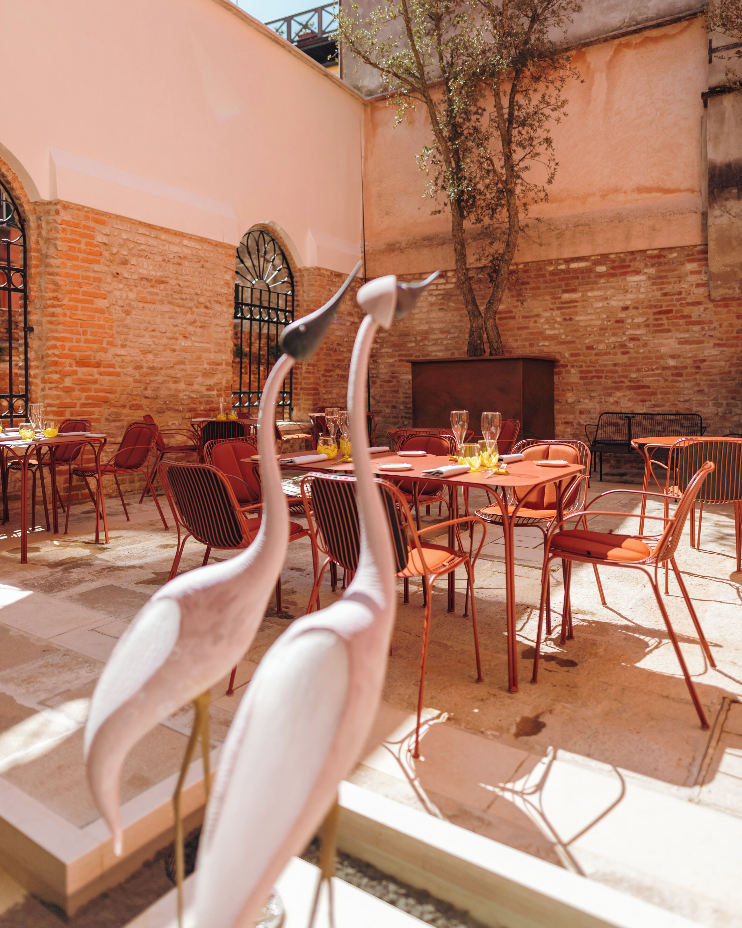An outdoor dining area with brick walls, metal chairs, and tables.