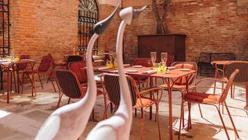 An outdoor dining area with brick walls, metal chairs, and tables.