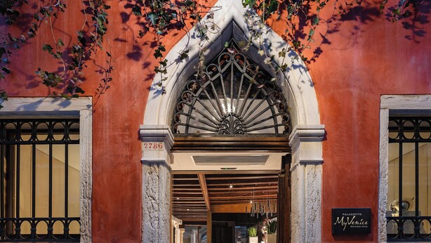 A hotel entrance with a wrought iron gate, a sign reading "Palazzo MyVenice Boutique Hotel," and a view into the interior. - Palazzetto My Venice (Venice)