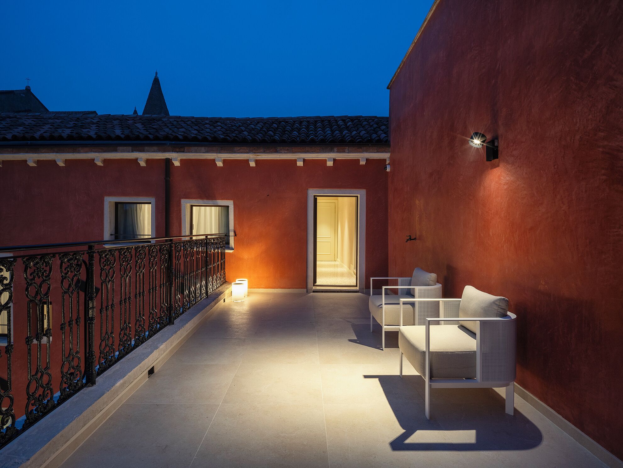 A balcony with a red wall, a white sofa, and a small table.