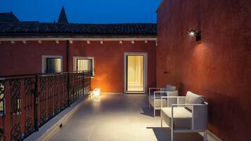 A balcony with a red wall, a white sofa, and a small table.