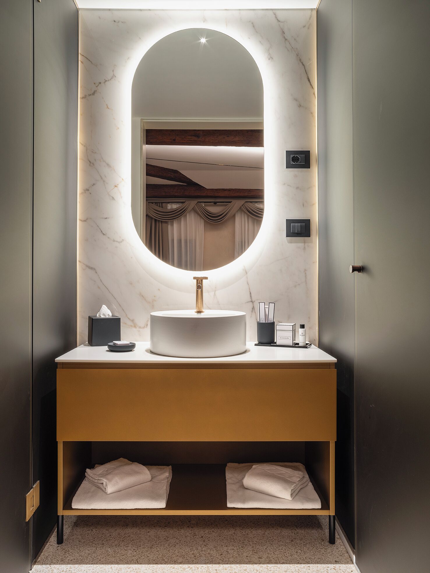 Ein modernes Badezimmer mit Marmorwaschtisch, rundem Spiegel und Handtuchhalter.