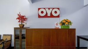 Een receptiegedeelte met een houten receptiebalie, een potrode boom en een bord met de tekst 'OYO'.