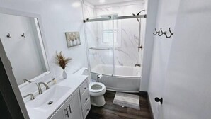 Een moderne badkamer met douche, toilet en wastafel.