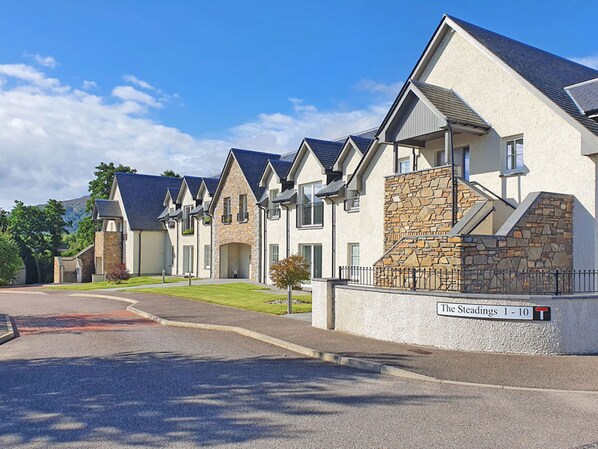 A row of modern, two-story houses with stone facades and pitched roofs, labeled "The Steadings 1 - 10".