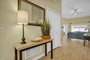 Relax in this spacious living area with a large mirror, console table, and ceiling fan.