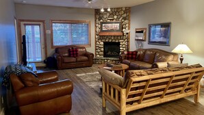 Una sala de estar con chimenea de piedra, sofás de cuero y un banco de madera.