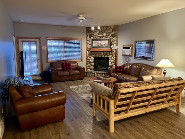 A living room with a stone fireplace, leather sofas, and a wooden bench.