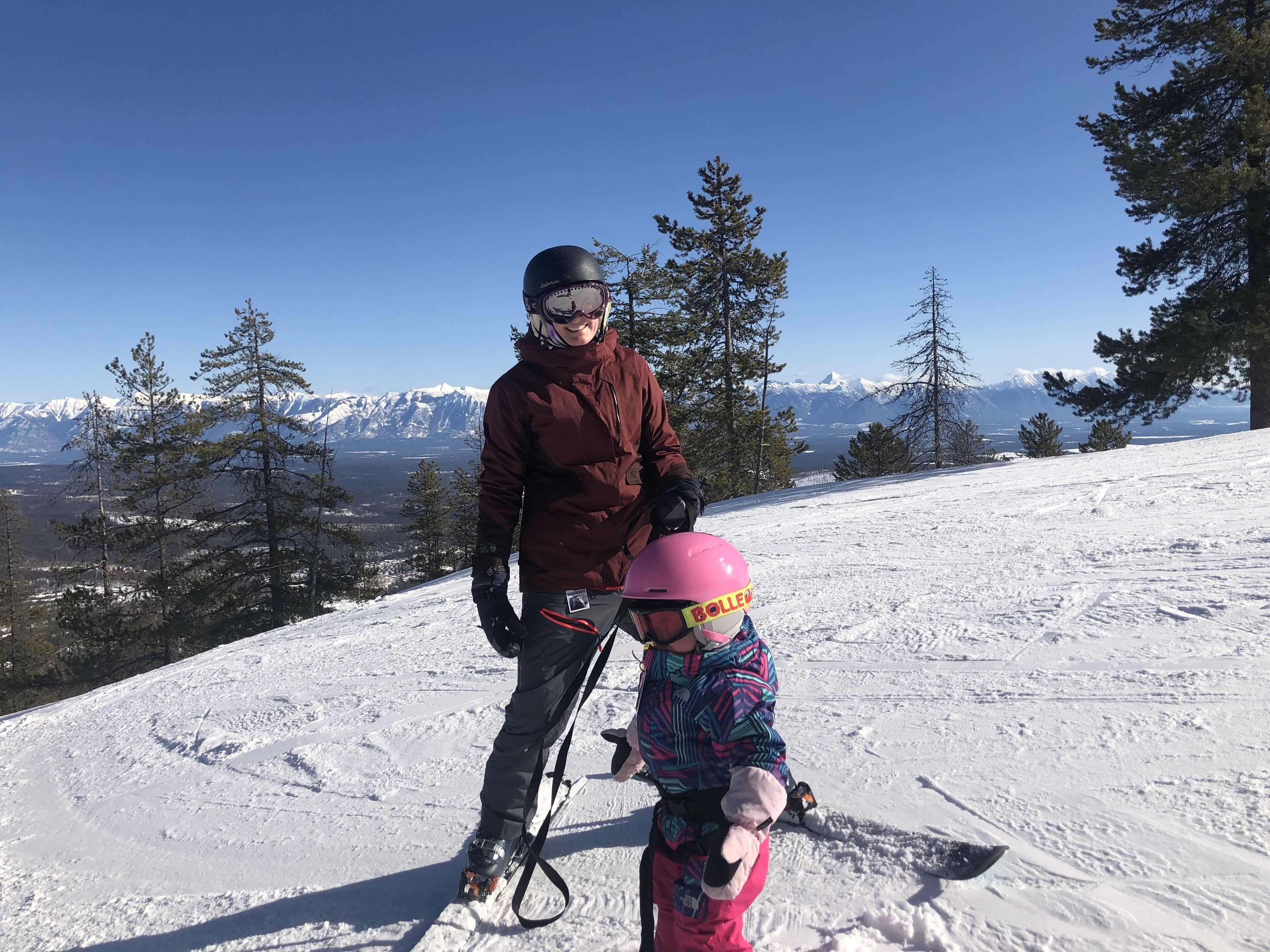 Une piste de ski enneigée où l’on voit une personne et un enfant en train de skier.