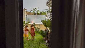 Dos niños de pie en un jardín con un letrero que dice "ZAMMA".