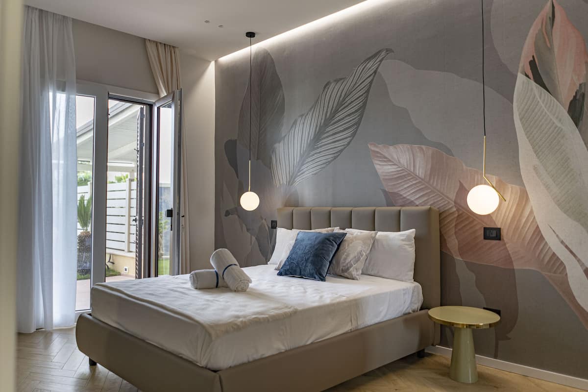 A modern bedroom with a large bed, a round side table, and a wall mural.