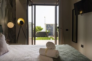 Quarto de hotel com cama, vista para o exterior e televisão presa na parede.