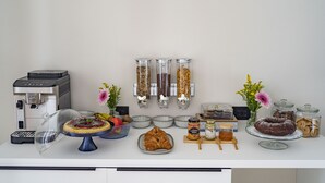 Un bufé de desayuno con cafetera, pasteles y acompañamientos.