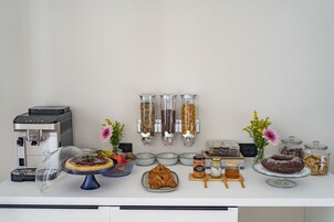 Um buffet de café da manhã com máquina de café, doces e acompanhamentos.