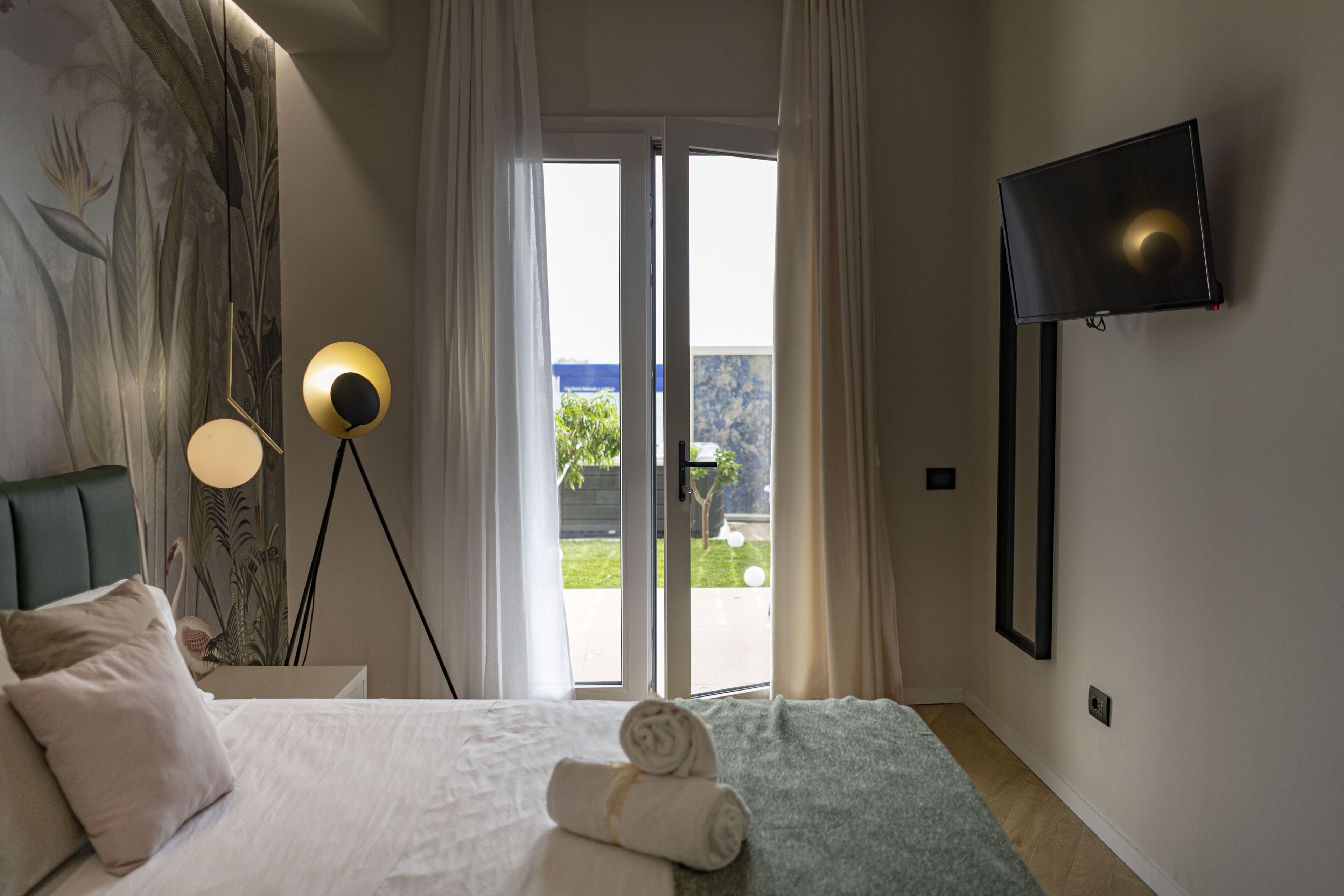 Ein Hotelzimmer mit einem Bett, einer Stehlampe, einem Flachbildfernseher und Blick durch die Tür.