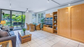 A modern living room with a sofa, wicker chairs, a coffee table, and a TV on a wooden cabinet. - 3-Min Walk to Beach! Ground Floor - No Resort Fee (Kihei)