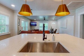 A modern kitchen with a central island, stainless steel sink, and pendant lighting.