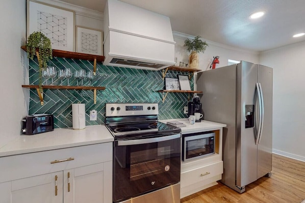 Una cocina moderna con un refrigerador de acero inoxidable, un horno empotrado y un microondas.