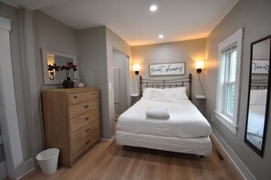 A bedroom with a bed, dresser, and a wall-mounted mirror. - Updated Historic Cape overlooking the famous Winnisquam Sandbar  (Belmont)