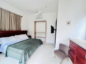 Un dormitorio con cama, una silla, un televisor y un armario.